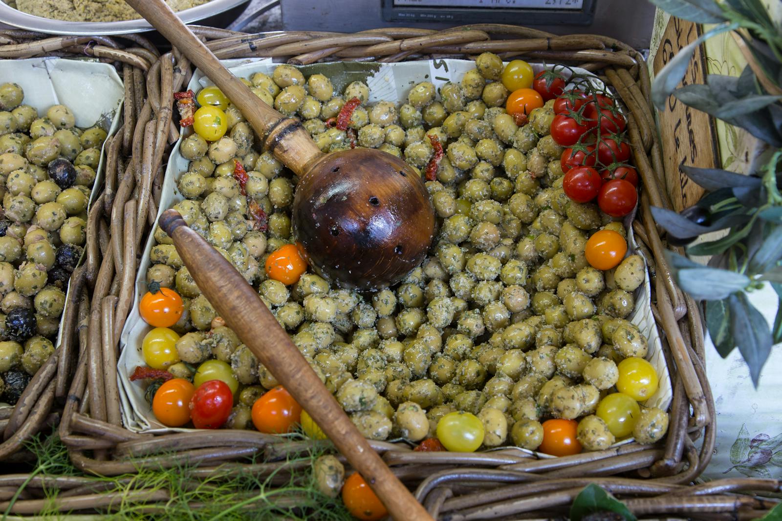 Olives de Provence marinées aux herbes et tomates cerises dans des paniers d'osier — les amuse-bouche du début de repas.